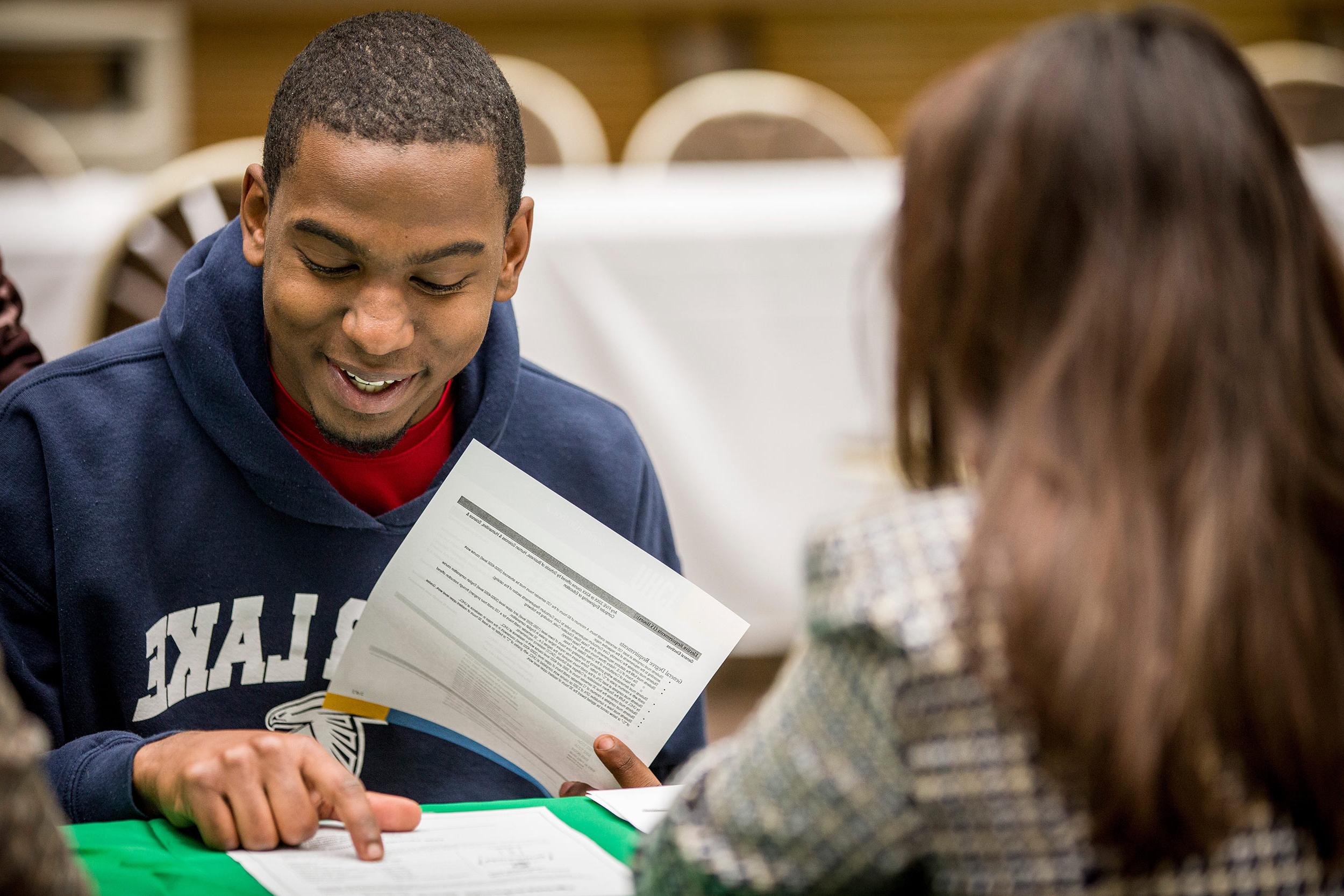 Student smiling and reading through papers